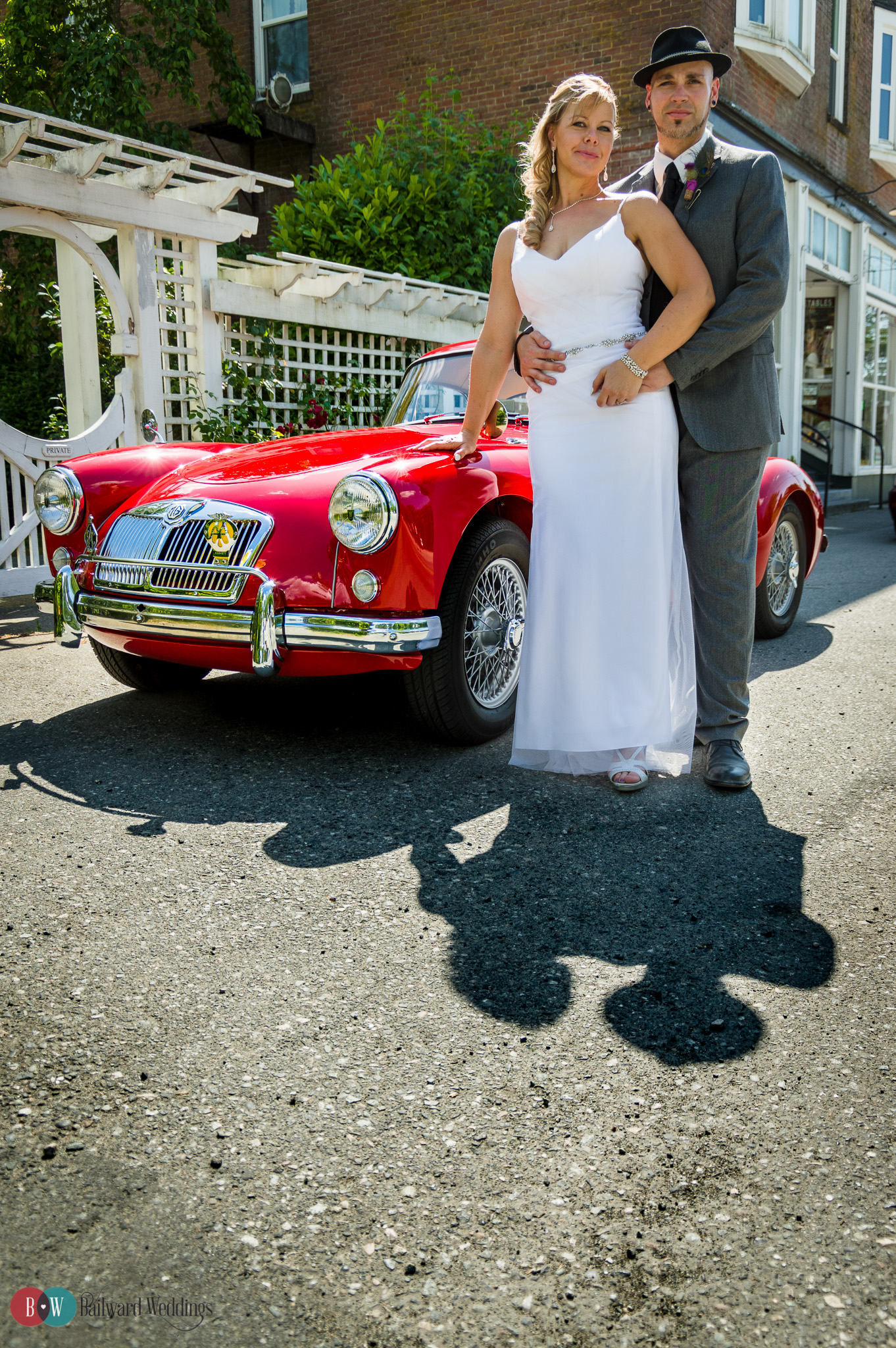 Bride and groom posing in front of classic car