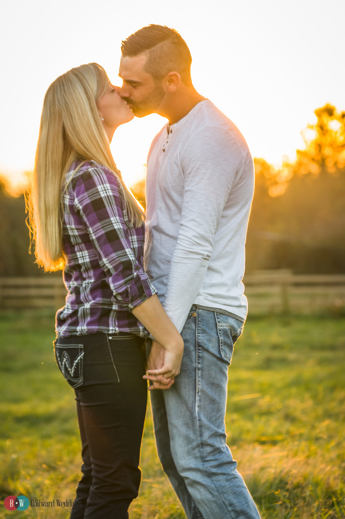 Engagement couple kissing in front of sunset