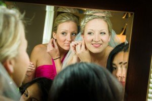 Bride and bridesmaids getting ready looking in mirror