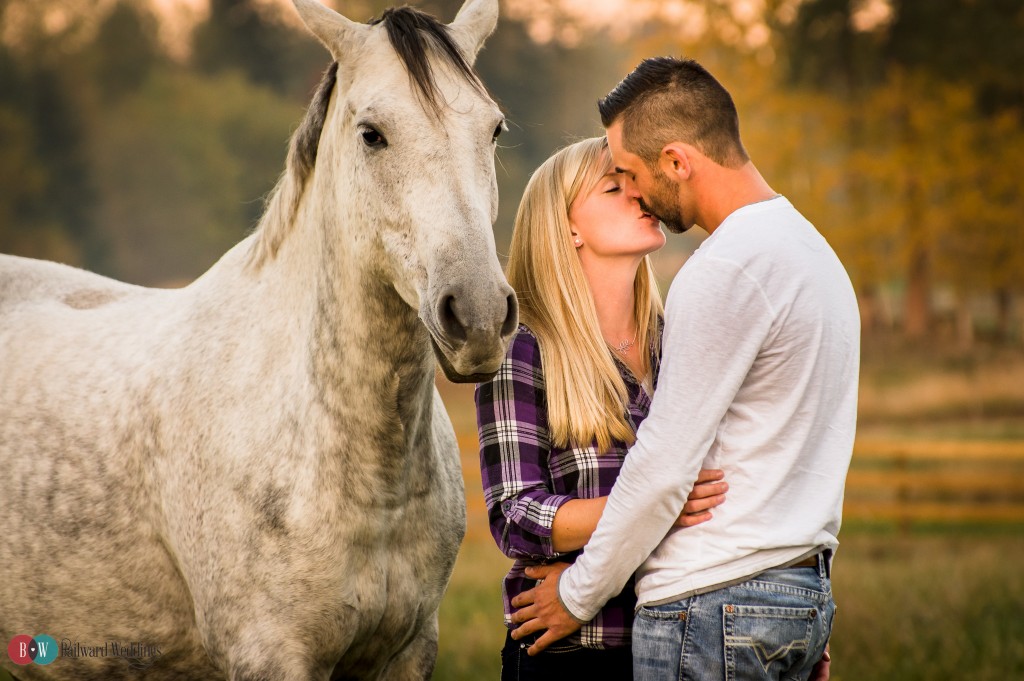 Engagement couple kissing by horse