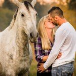 Engagement couple kissing by horse