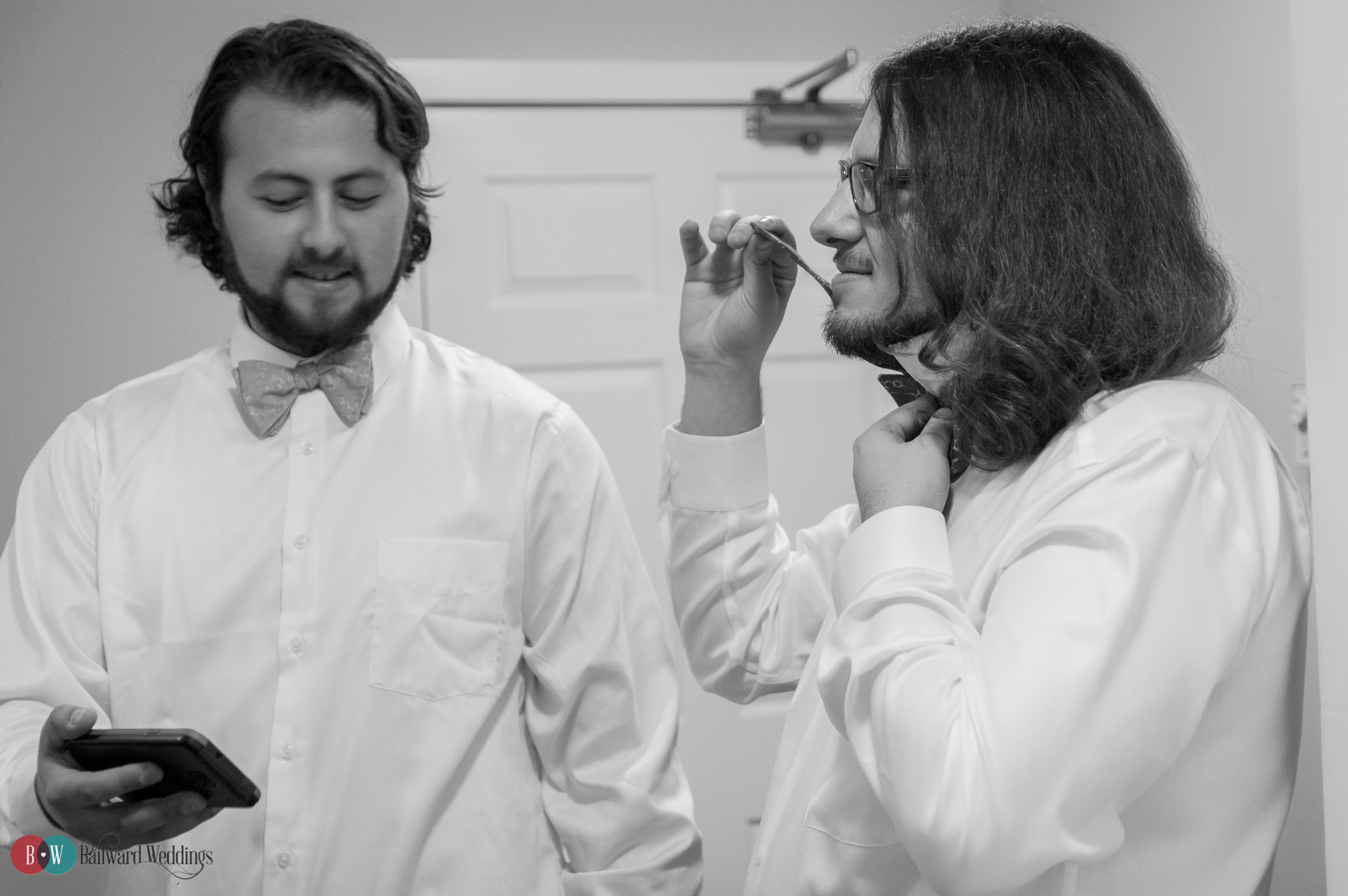 Groom and best man tying bow ties