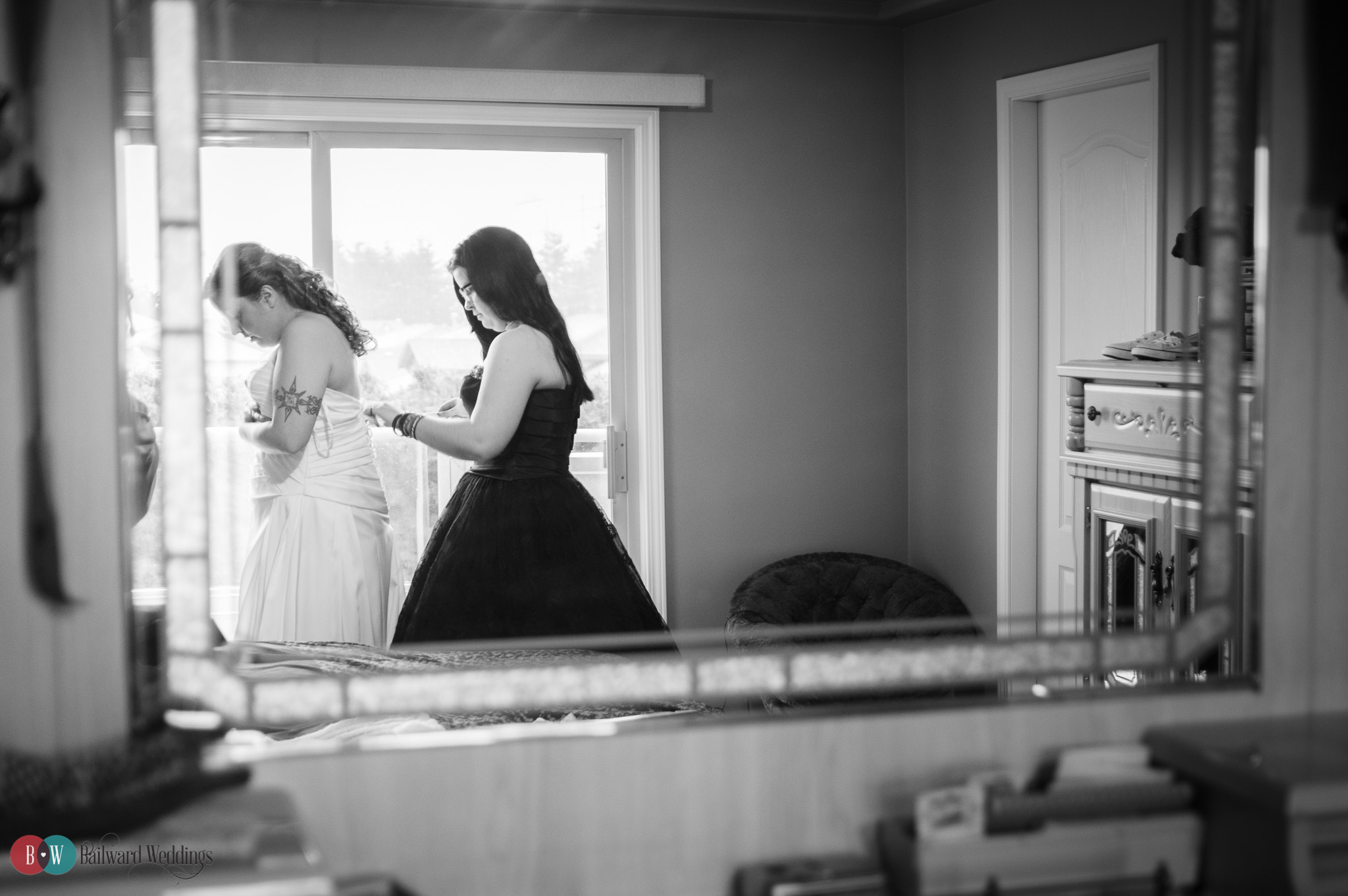 Bridesmaid getting bride ready in wedding dress