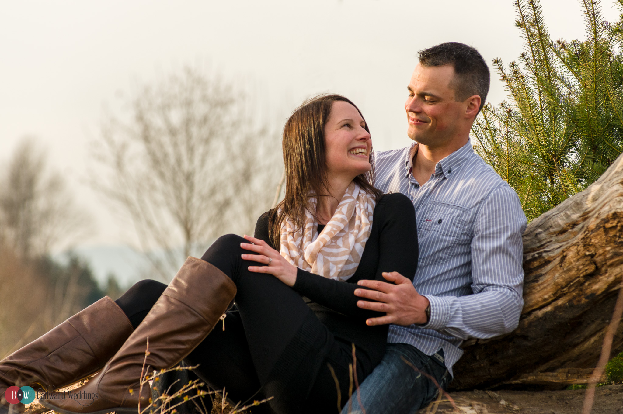 Engaged couple smiling at each other on tree